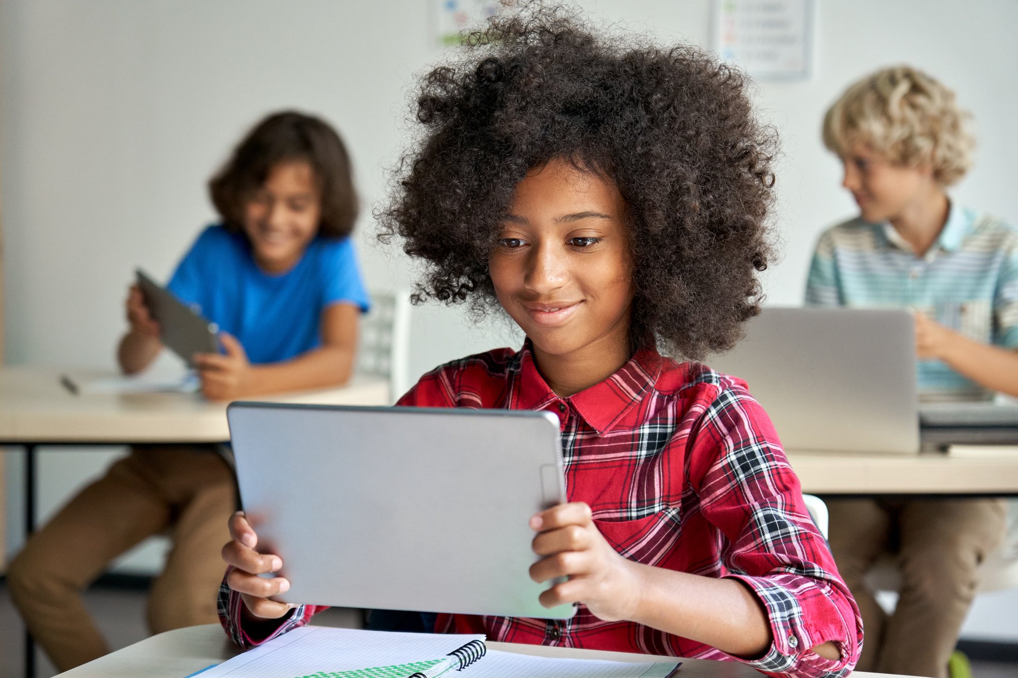 Happy school girl holding tablet in classroom Happy school girl holding tablet in classroom